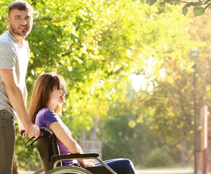 un homme pousse une femme en fauteuil roulant